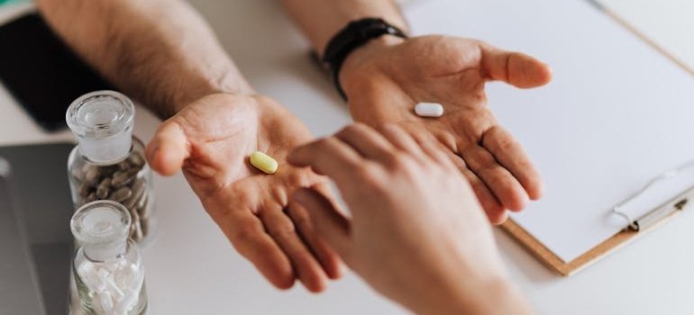 Doctor offering two pills to a patient.