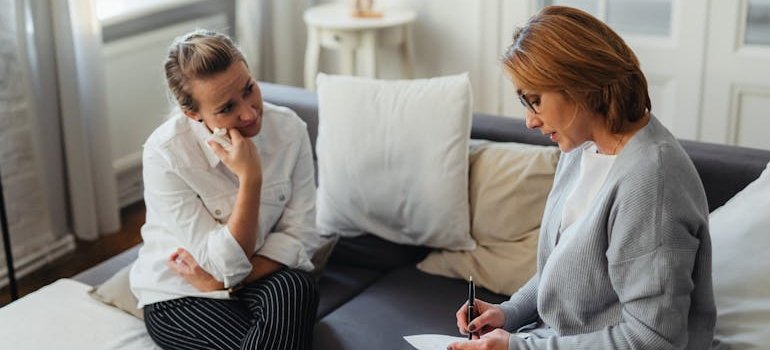 Therapist writing in her notebook while talking to a therapist.