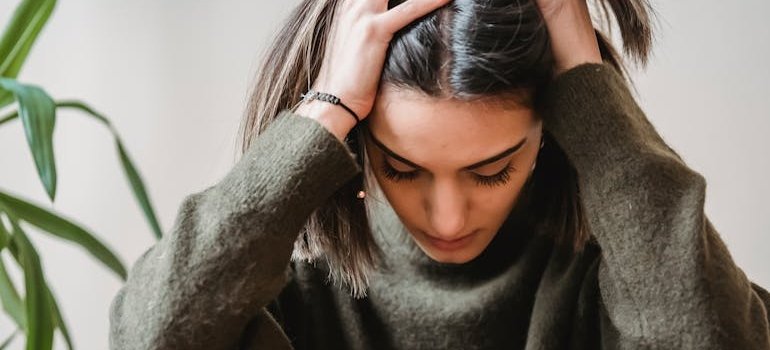 Woman holding her head and experiencing personality change when drinking alcohol.