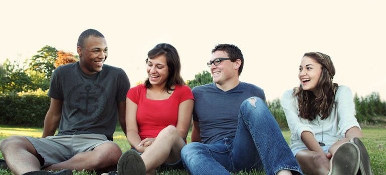Four friends sitting on the grass and laughing.