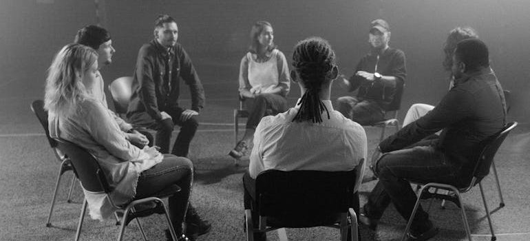 Support group sitting in a circle and talking about crack addicts before and after.