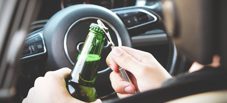 Man opening a beer bottle while sitting in a car.