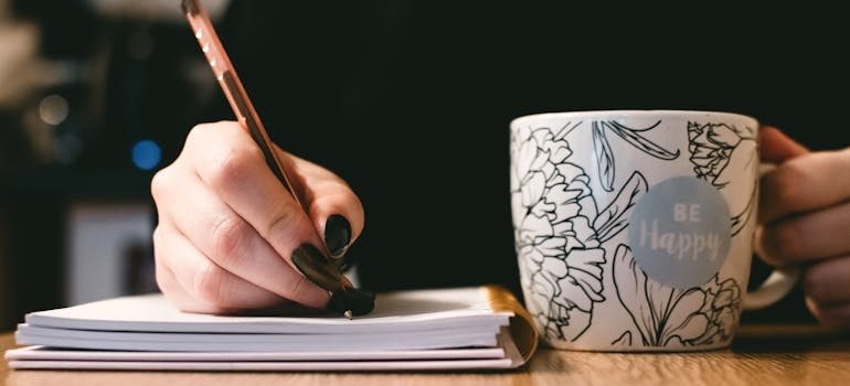 Woman drinking tea and writing in a journal.