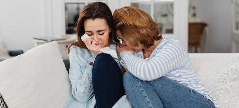 Two women crying and hugging each other.