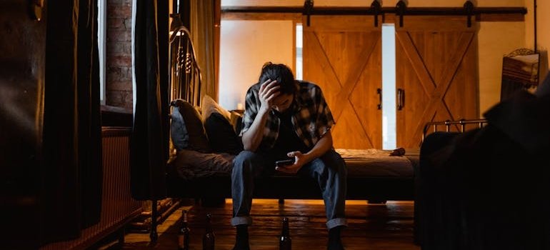 Man sitting on the bed and looking at his phone.
