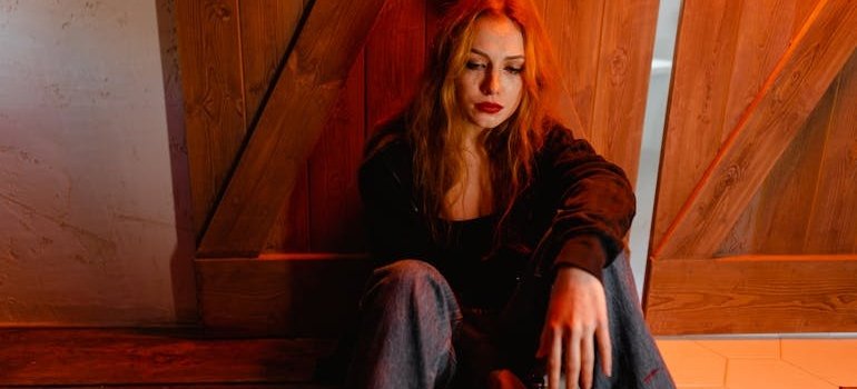 Woman sitting on the floor and holding a beer bottle.