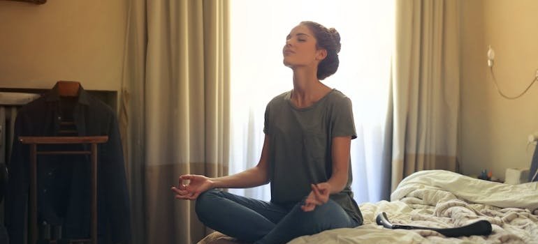 Woman sitting on the bed and meditating to deal with setbacks in recovery.
