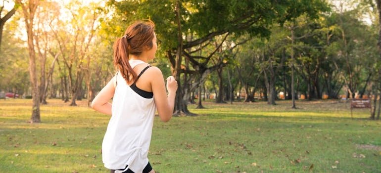 Woman wearing a white top running in the park.