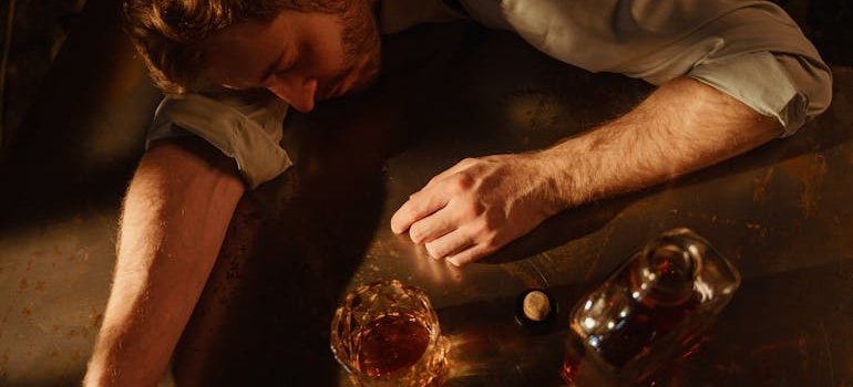 Man lying on a table while drinking whiskey.