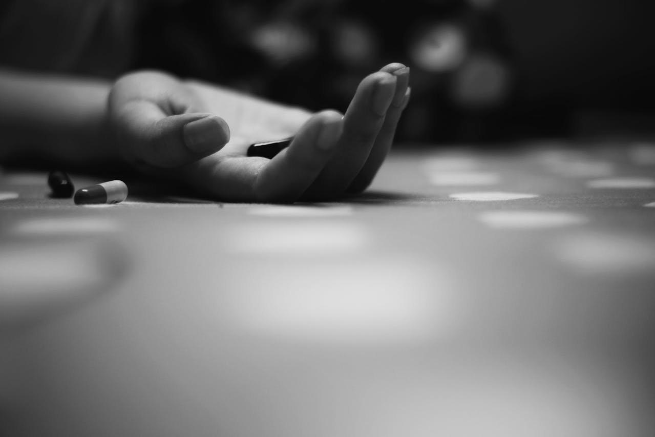 Person's hand on the floor holding pills.