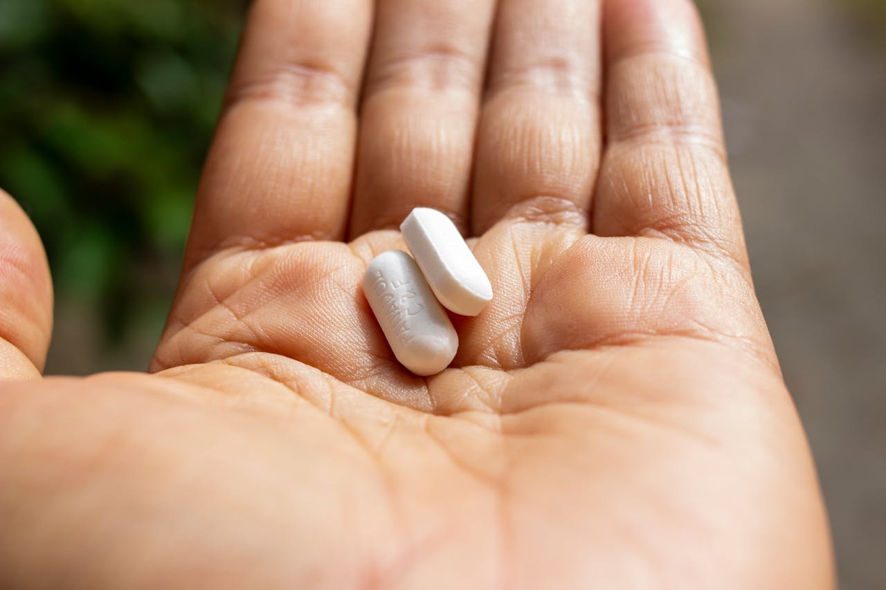 Person holding two pills in their hand.