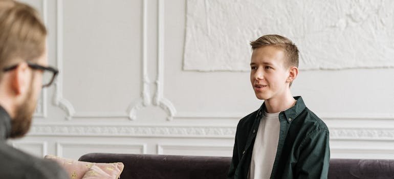 Young man talking about his issues with alcohol abuse and poverty with his therapist.