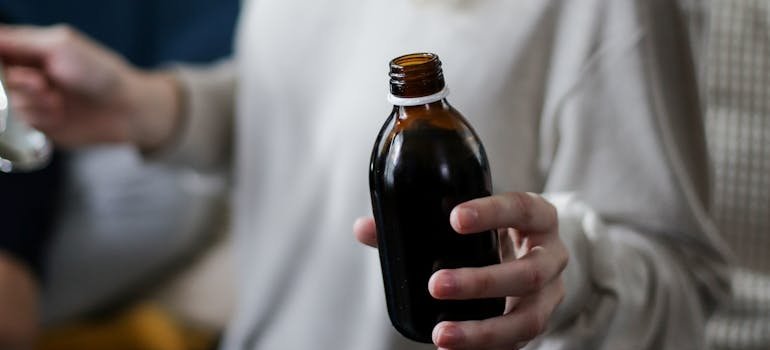 Woman holding a bottle of cough syrup.