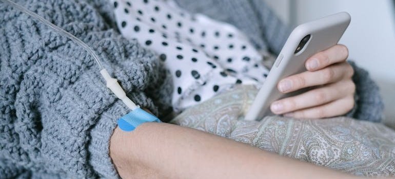 Woman using her phone while receiving an IV.