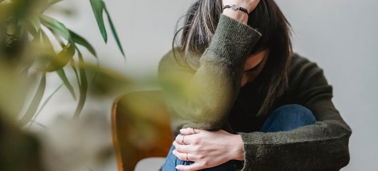 Woman sitting on a chair and holding her head.