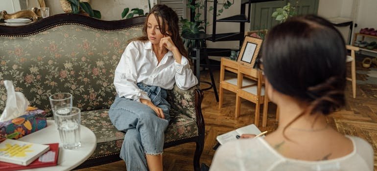 Woman worrying about how to go to rehab without losing your job while talking to her therapist.