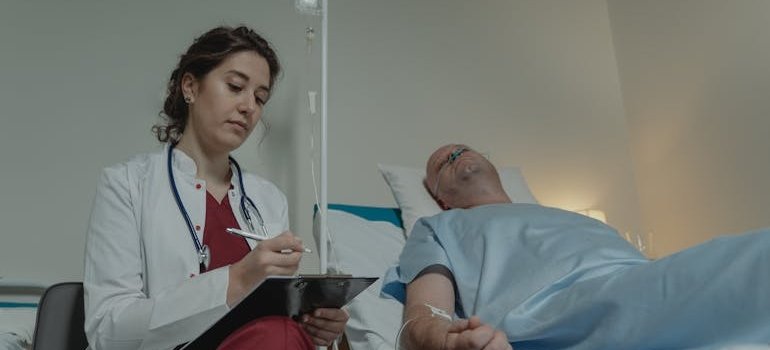 Doctor writing on a clipboard while talking to a patient.