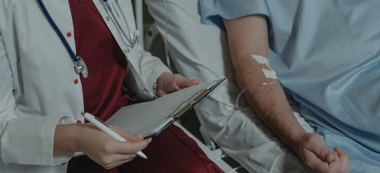 Doctor talking about how drugs influence a person's emotions, perceptions, and behavior to a patient lying in a hospital bed.