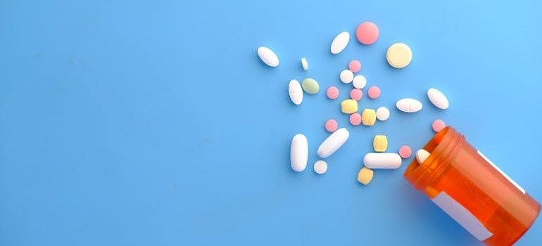 Different colored pills falling out of a pill bottle.