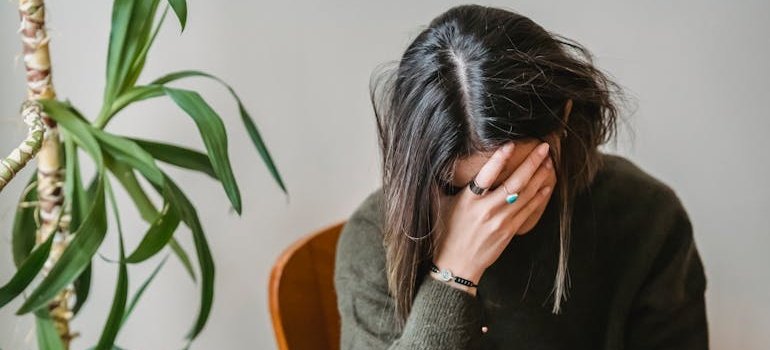 Woman sitting on a chair and covering her face.