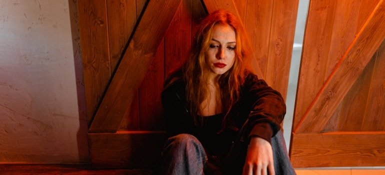 Woman sitting on the floor and crying while thinking about drugs and personality types.