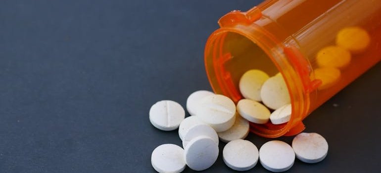 Pills spilling out of an orange bottle.