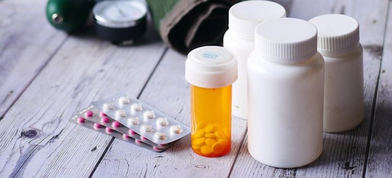 Bottles and blisters of pills on a wooden table.