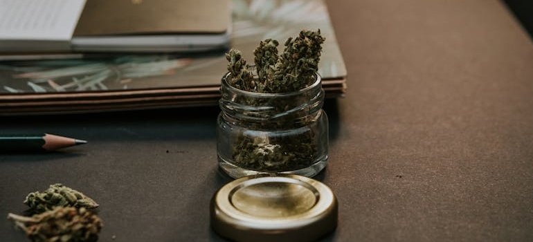 Marijuana in a jar on a wooden table.