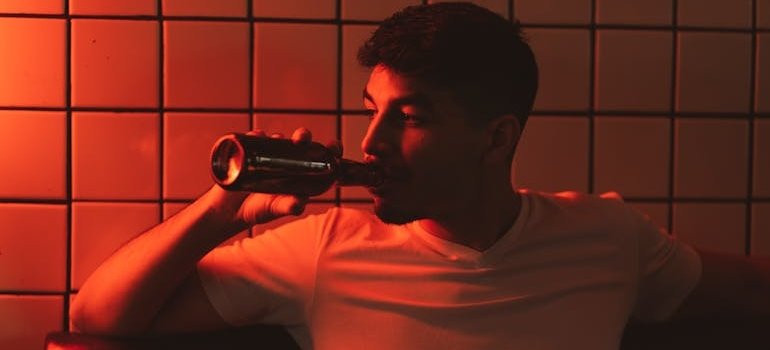 Man struggling with BPD and alcohol use drinking a beer bottle.