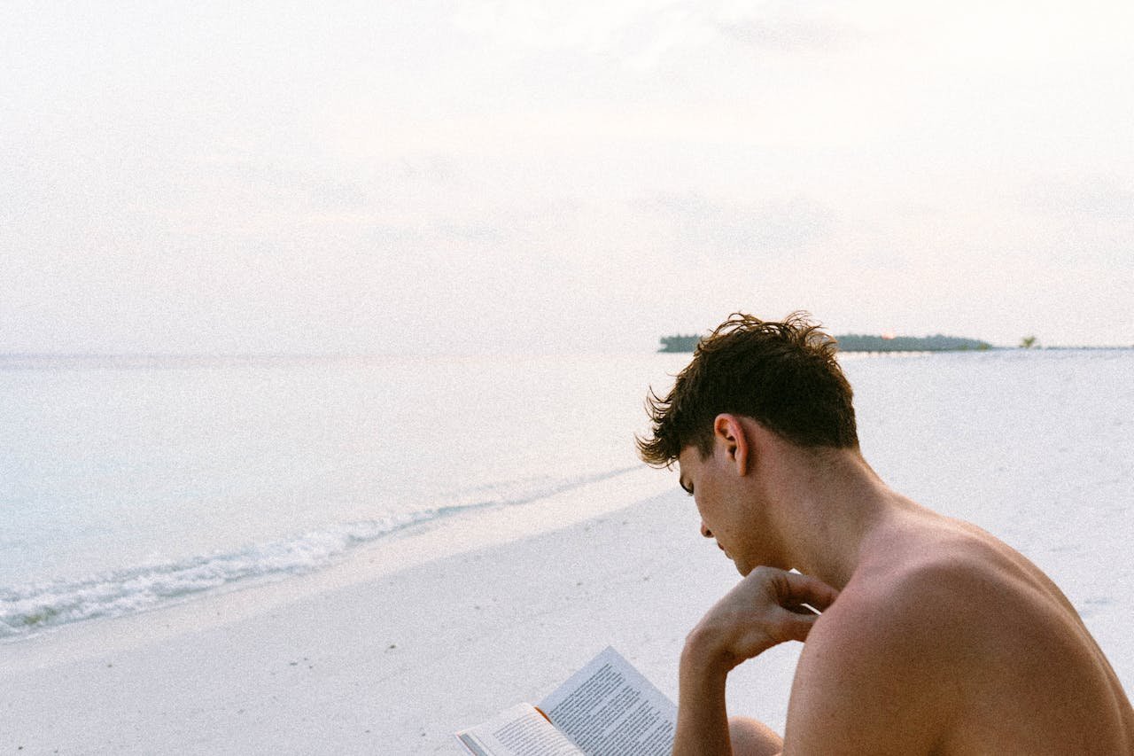 Man reading best stress management books on a beach.
