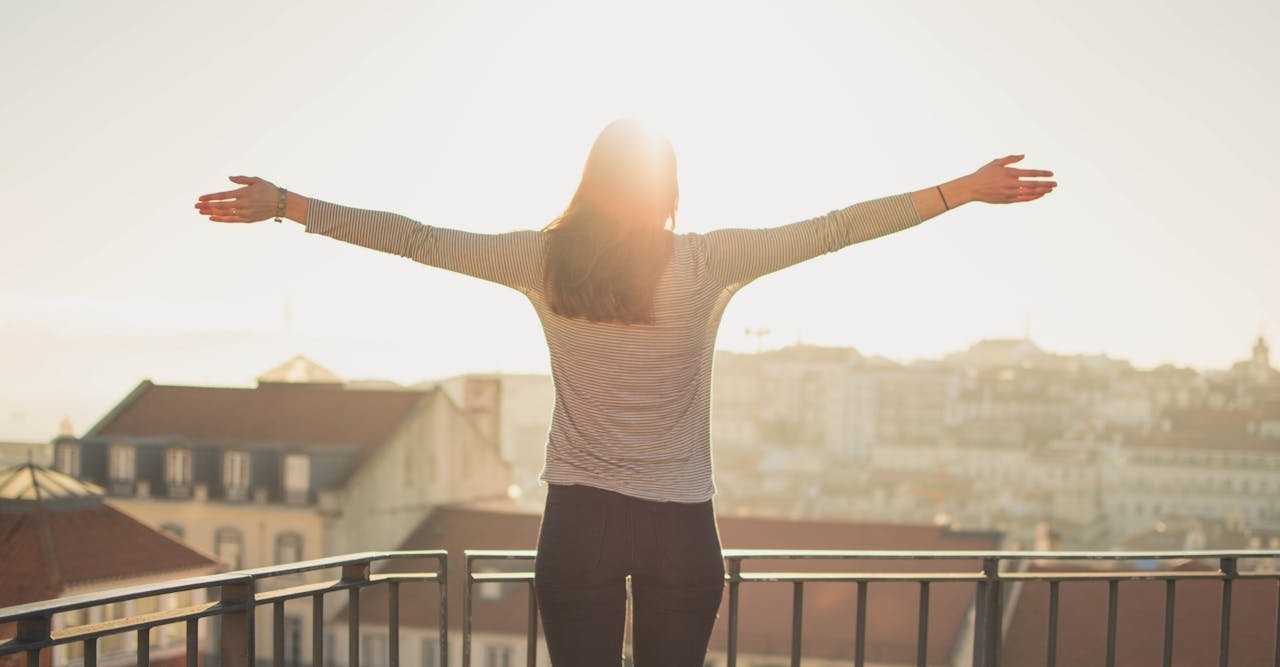 Woman spreading her arms while looking at the sun.