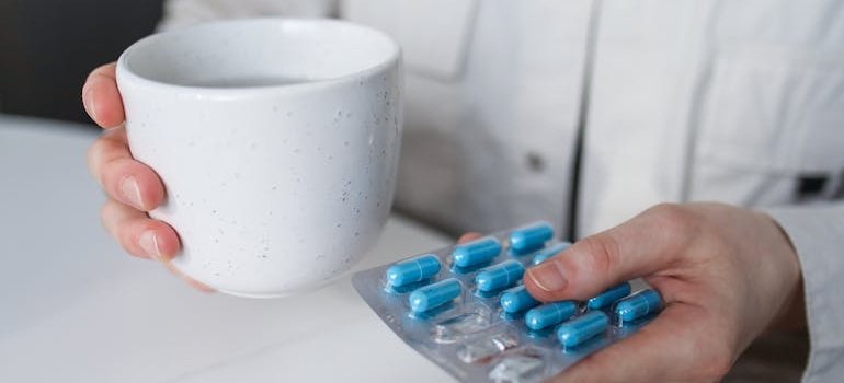Doctor holding a blister of pills and a glass of water.