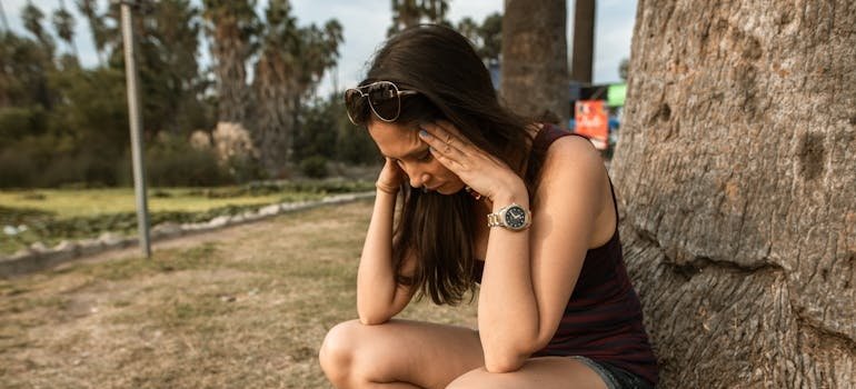 Woman sitting next to a trip and experiencing anxiety during sober vacations.