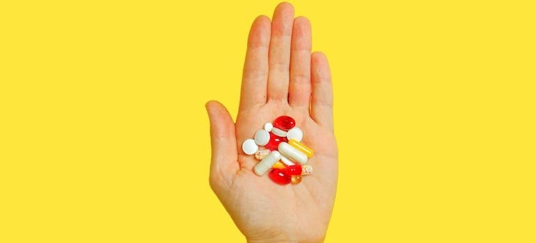 Person holding many different vitamin pills in their hand.