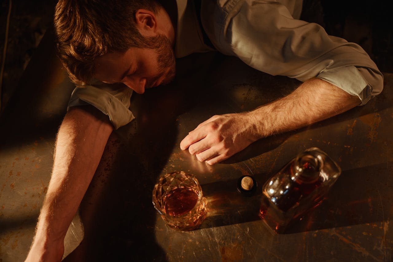Man lying on the table with a glass of whiskey.