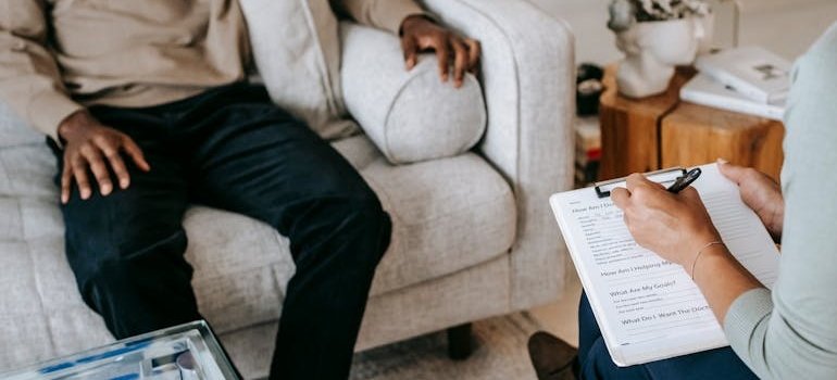 Therapist writing in a clipboard while talking about how to rebuild your life with a client.