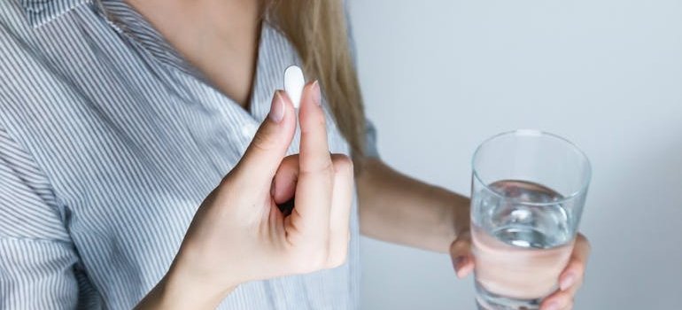 Woman holding a Xanax pill and a glass of water.
