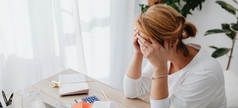 Woman covering her face while looking at her bills.
