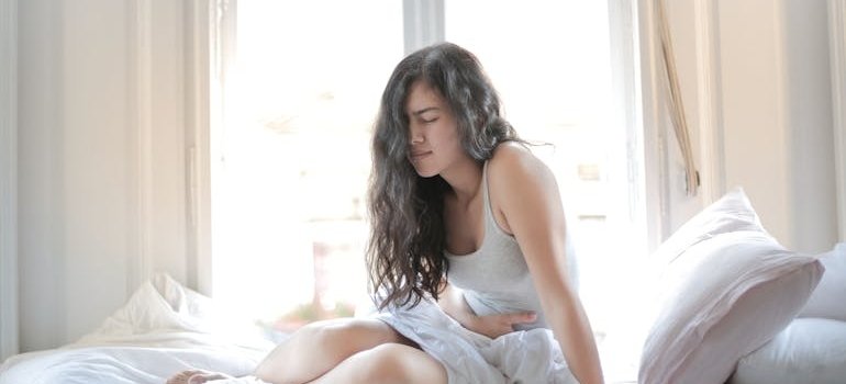 Woman sitting in bed with a stomachache.