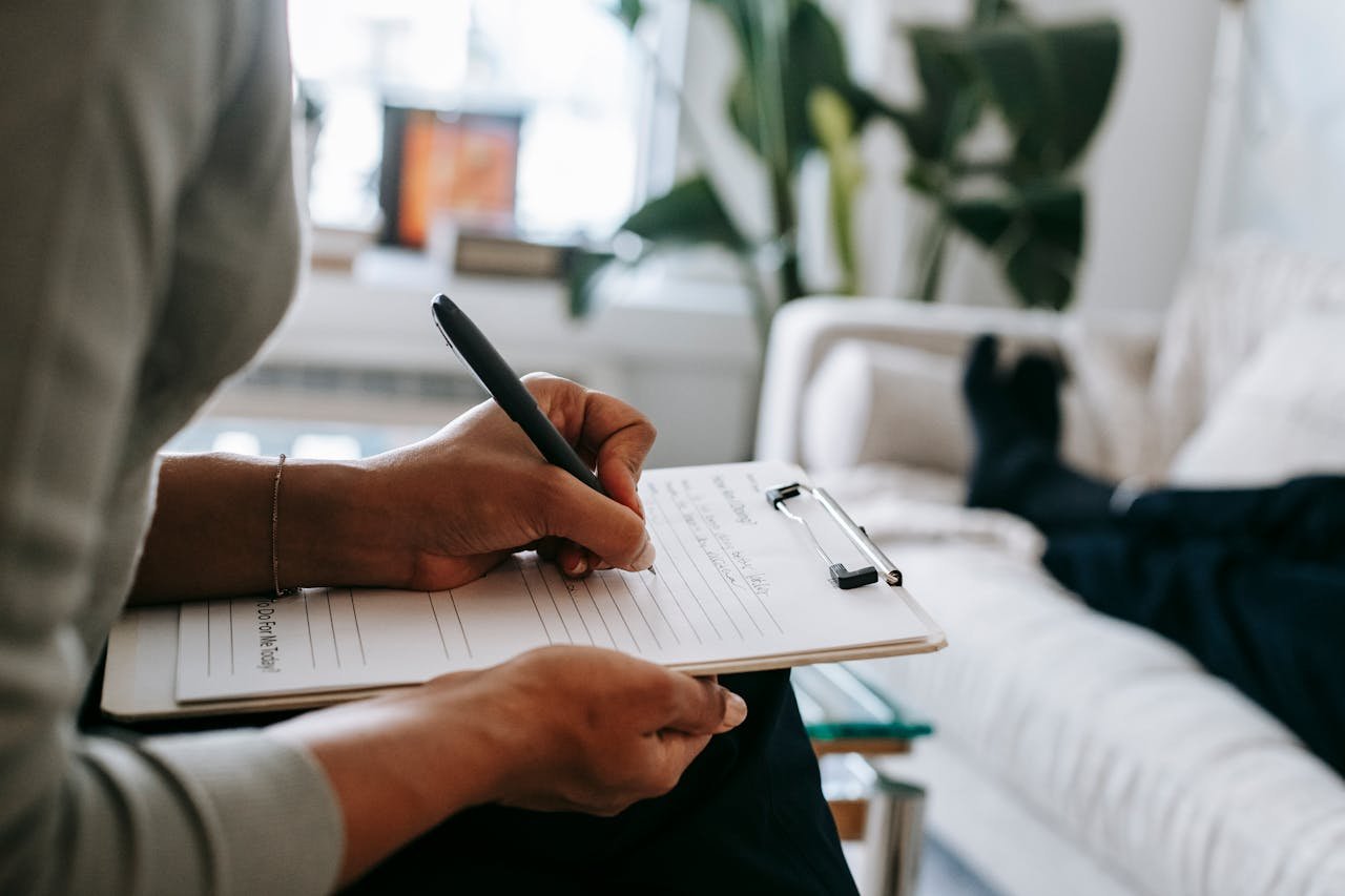Woman writing in a clipboard while talking to a client and doing an evaluation.