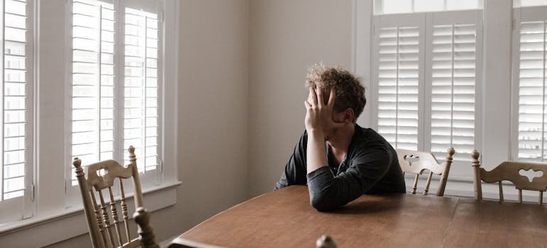 Man sitting at a table and worrying about his problems with dual diagnosis eating disorders and substance abuse.