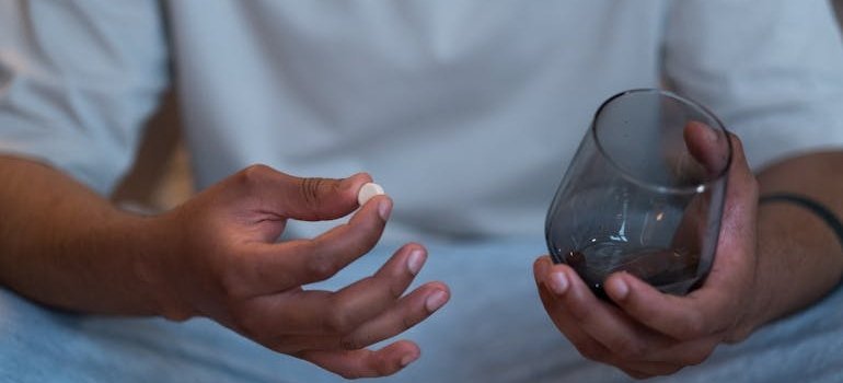 Man holding a pill and a glass of water.