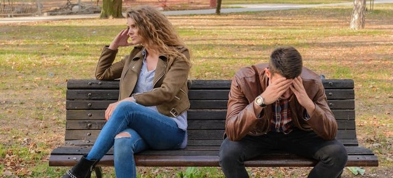 Couple sitting on a bench in the park after having an argument.