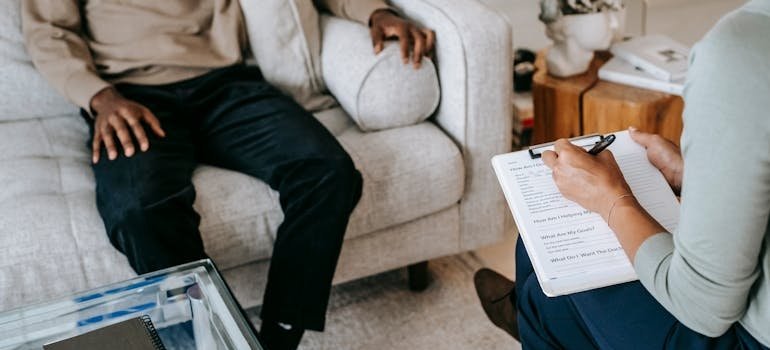 Woman writing in a clipboard while talking to a patient.