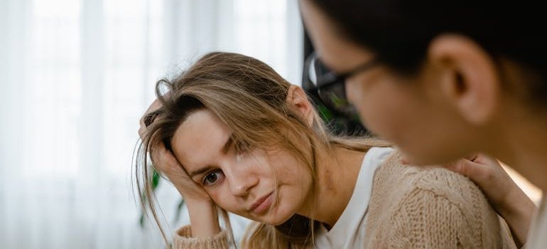 Woman comforting her friend while thinking about what to do when someone relapses.