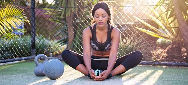 Woman stretching before doing outdoors weightlifting exercises.