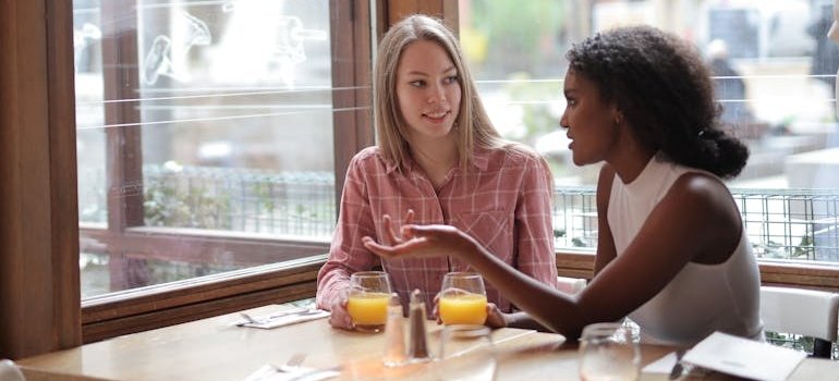 Two friends sitting at a restaurant and drinking juice.