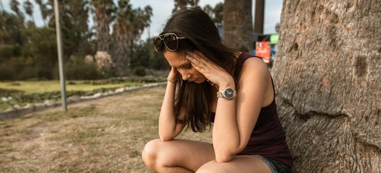 Woman crouching near a tree experiencing an anxiety attack.