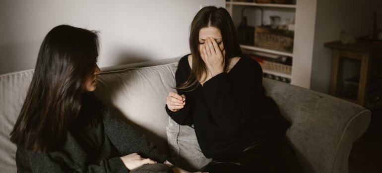 Woman comforting her friend while thinking about what to do when someone relapses.
