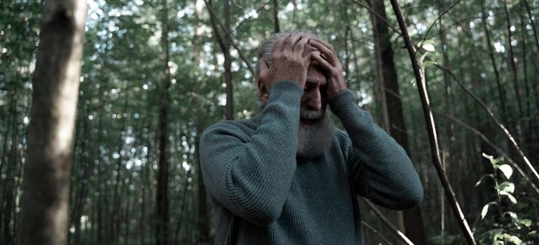Man having a headache in the middle of the woods.